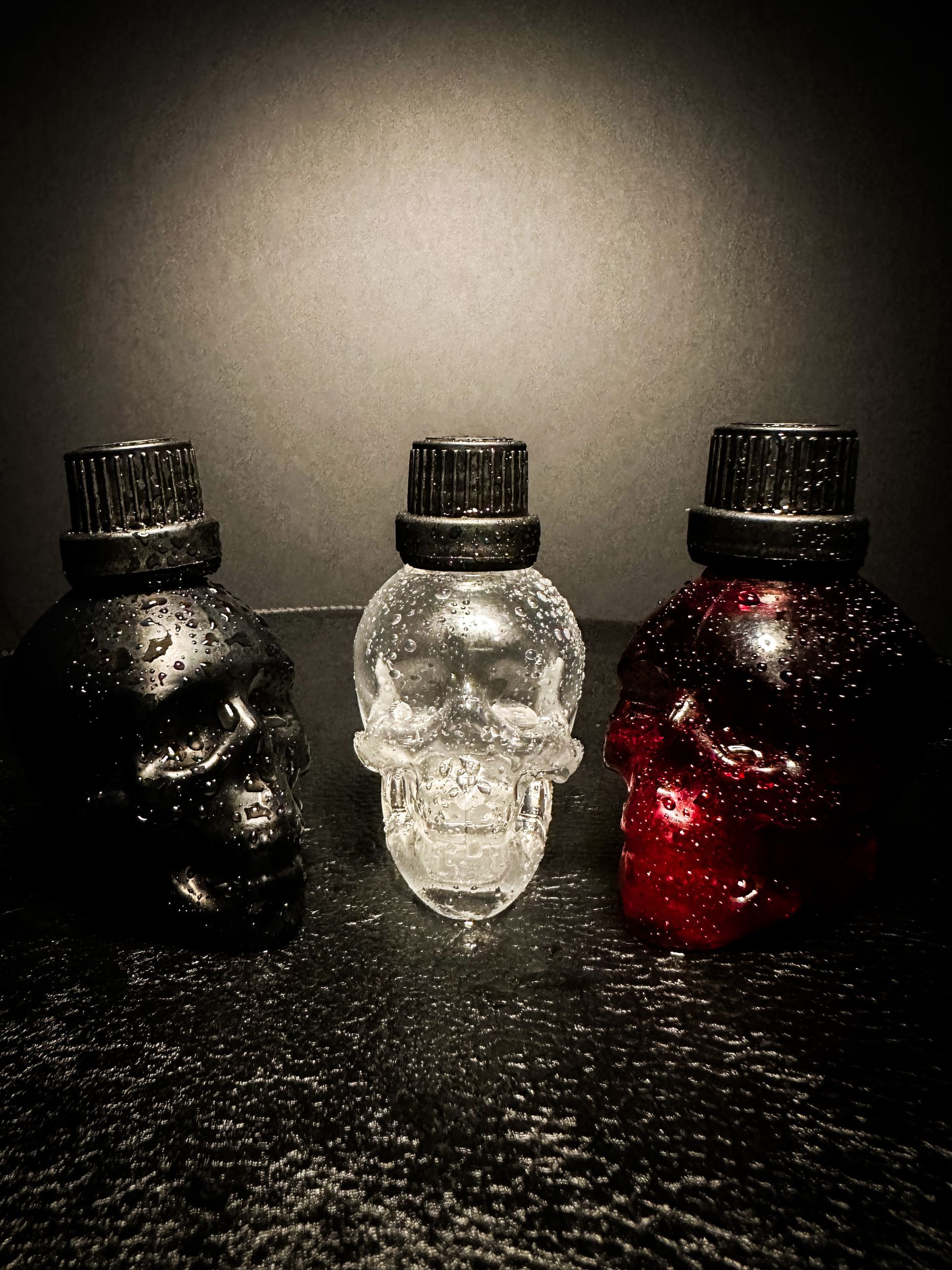 Three skull shaped bottles are sitting on a table.