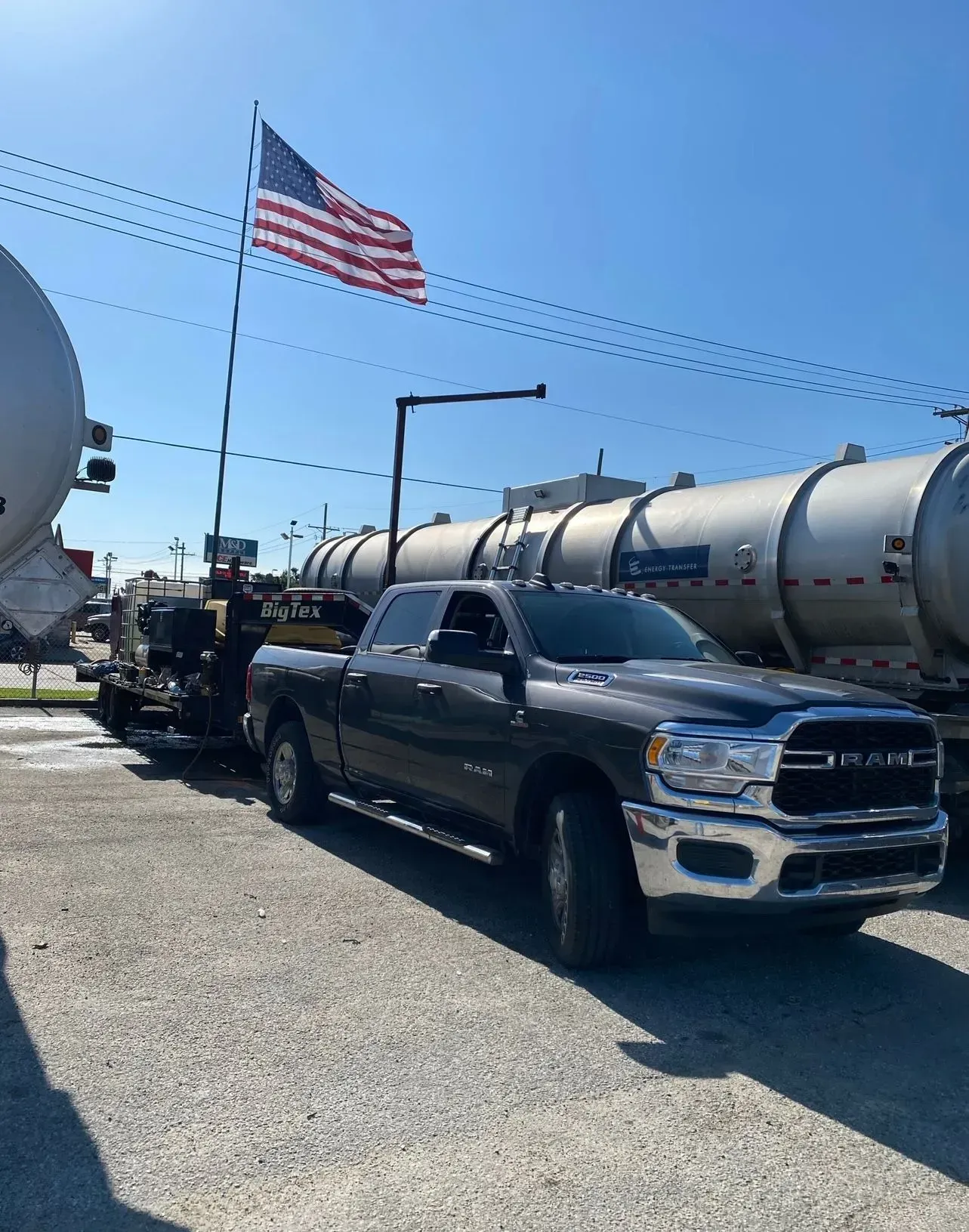 A gray truck is parked in front of a large tank.