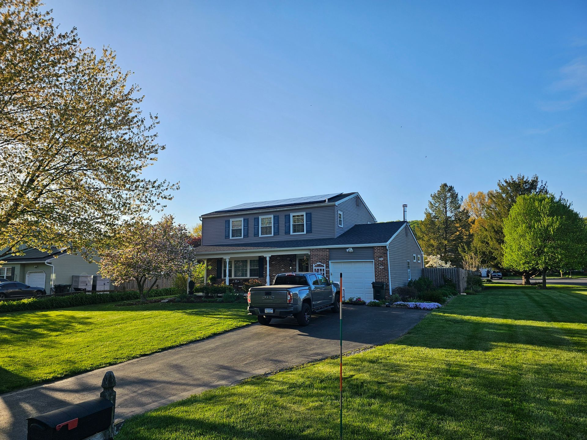 A truck is parked in front of a house with solar panels on the roof.