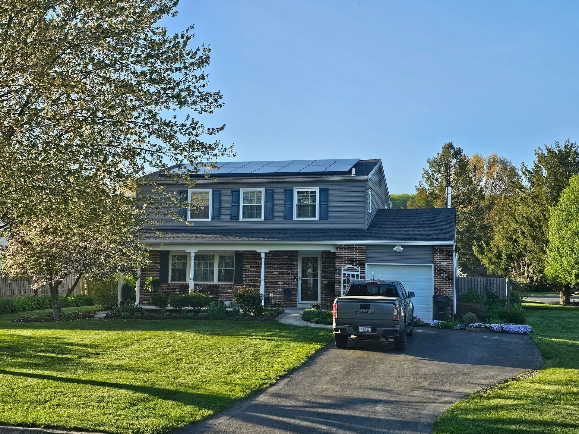 A truck is parked in front of a house with solar panels on the roof