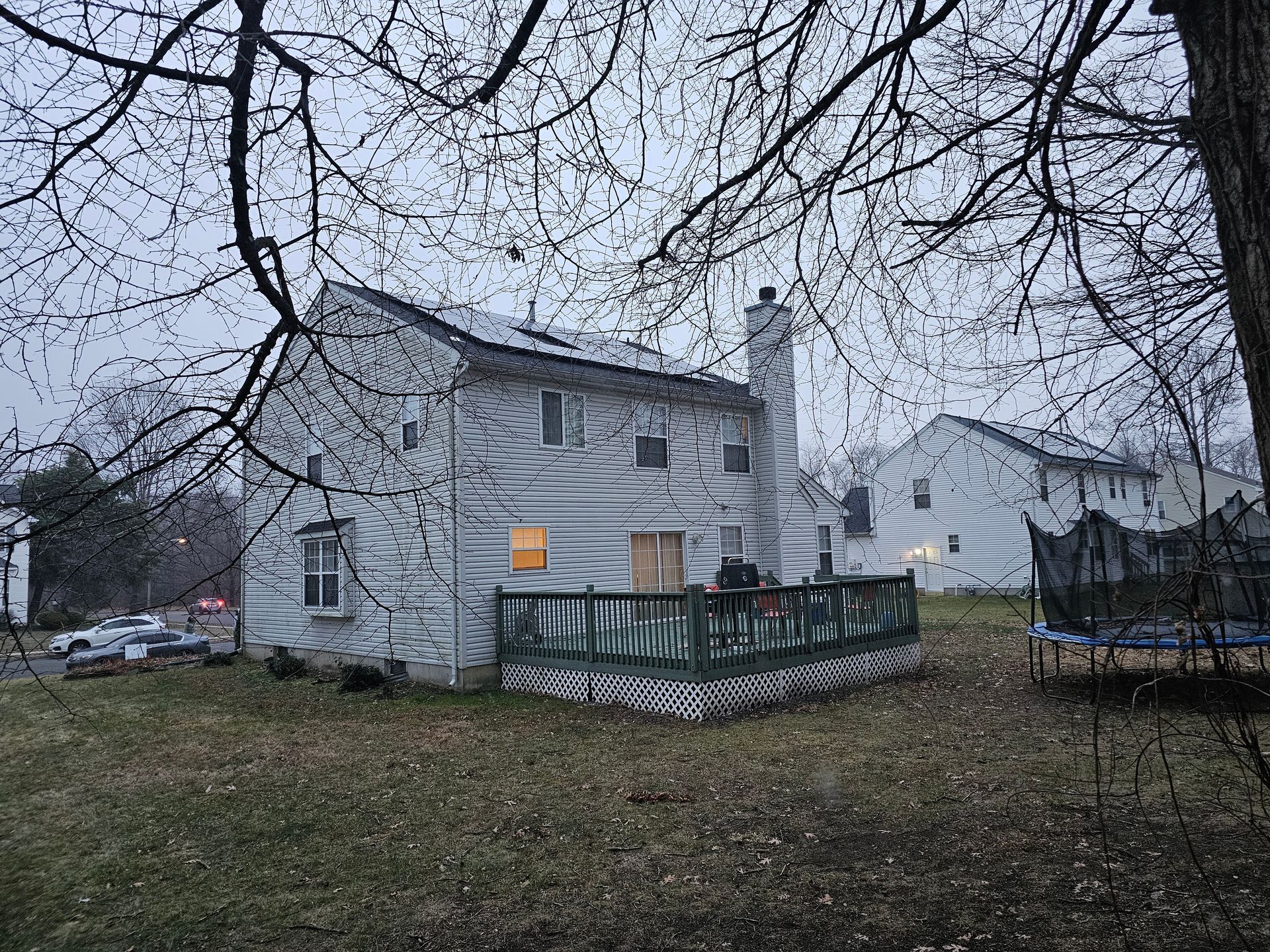 The backyard of a house with a trampoline in the grass.