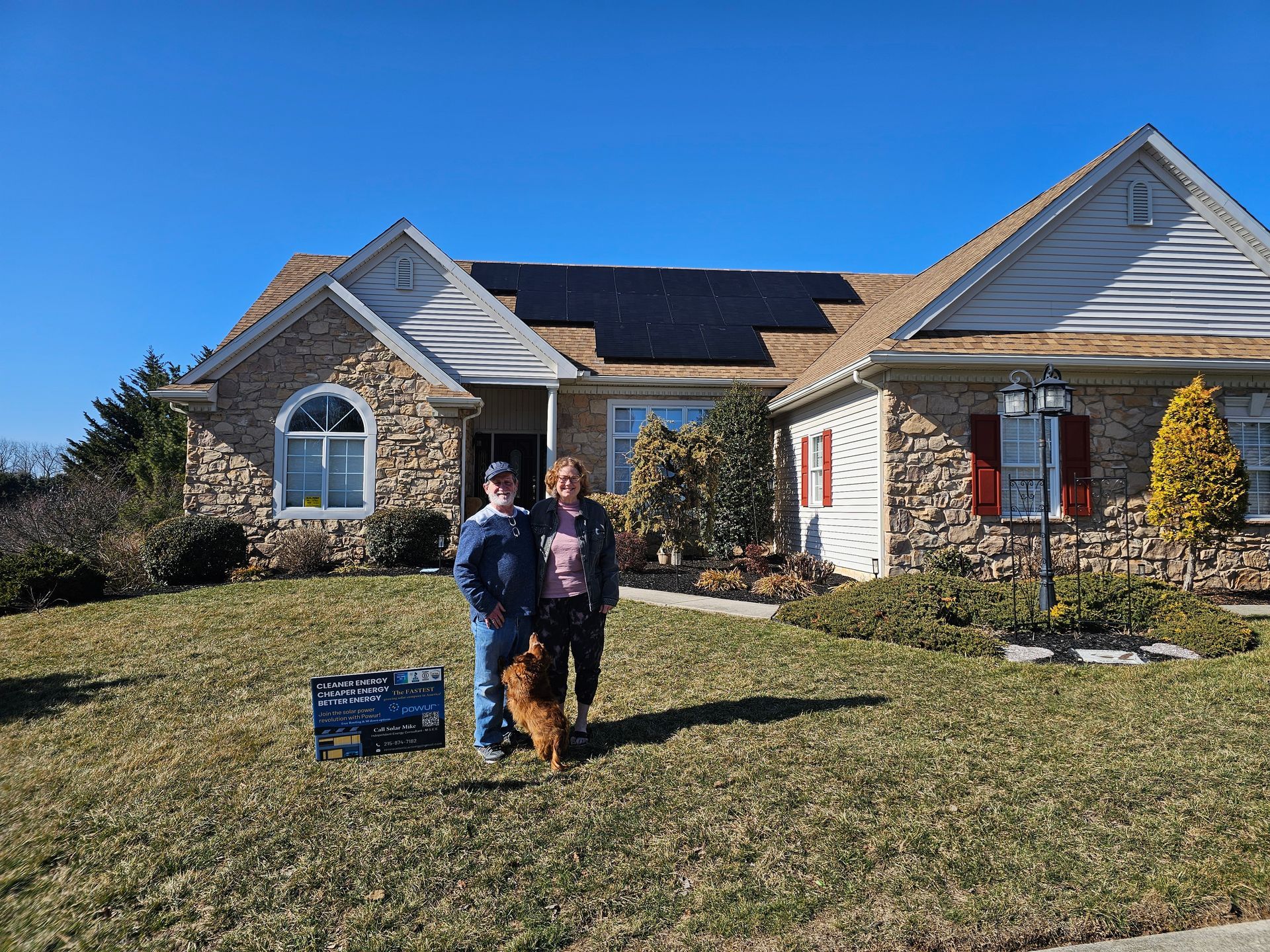 A man and woman are standing in front of a house with solar panels on the roof.