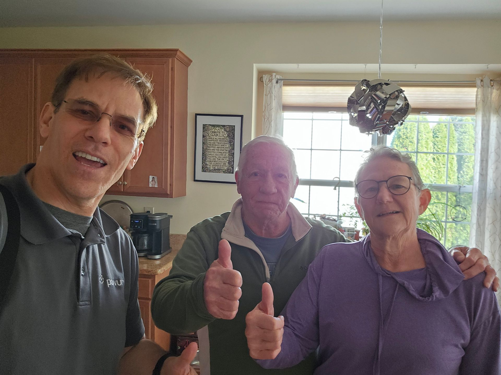 A man and two women are giving a thumbs up in a kitchen.