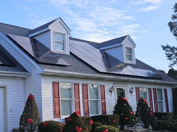 A white house with red shutters and solar panels on the roof