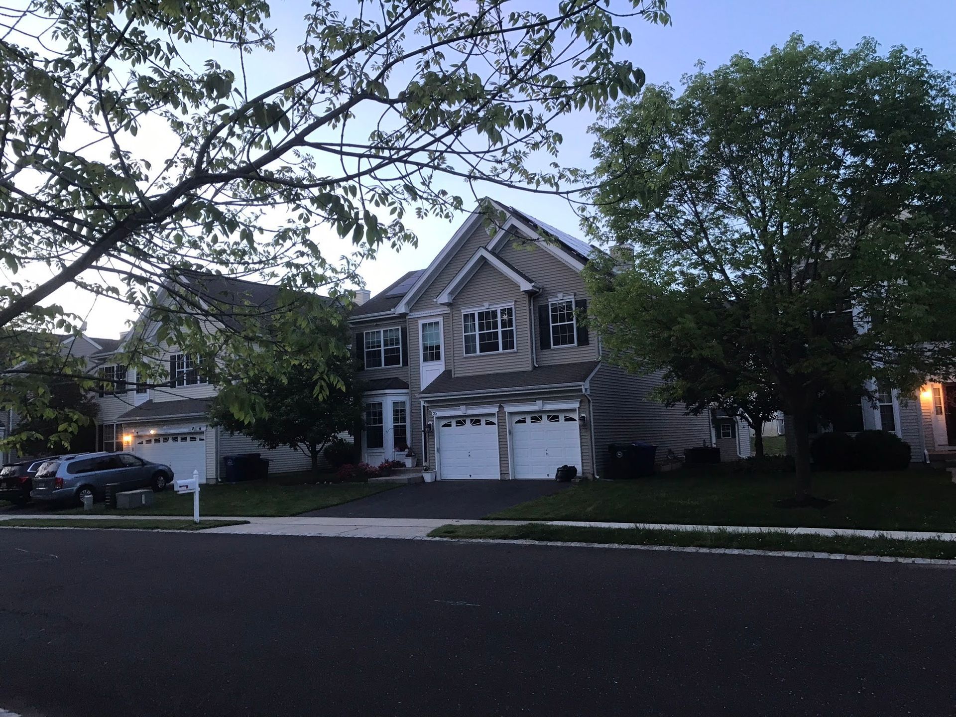 A large house with two garages is surrounded by trees