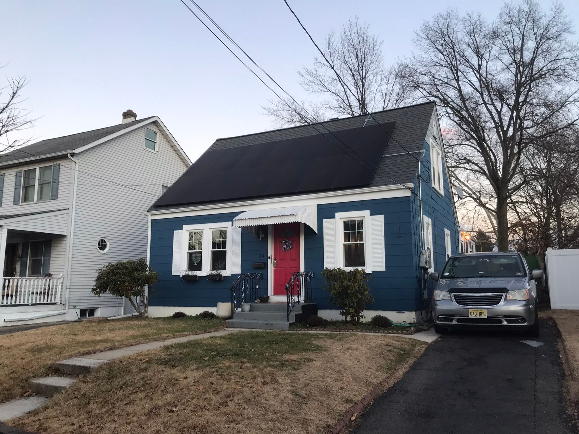 A blue house with a car parked in front of it.