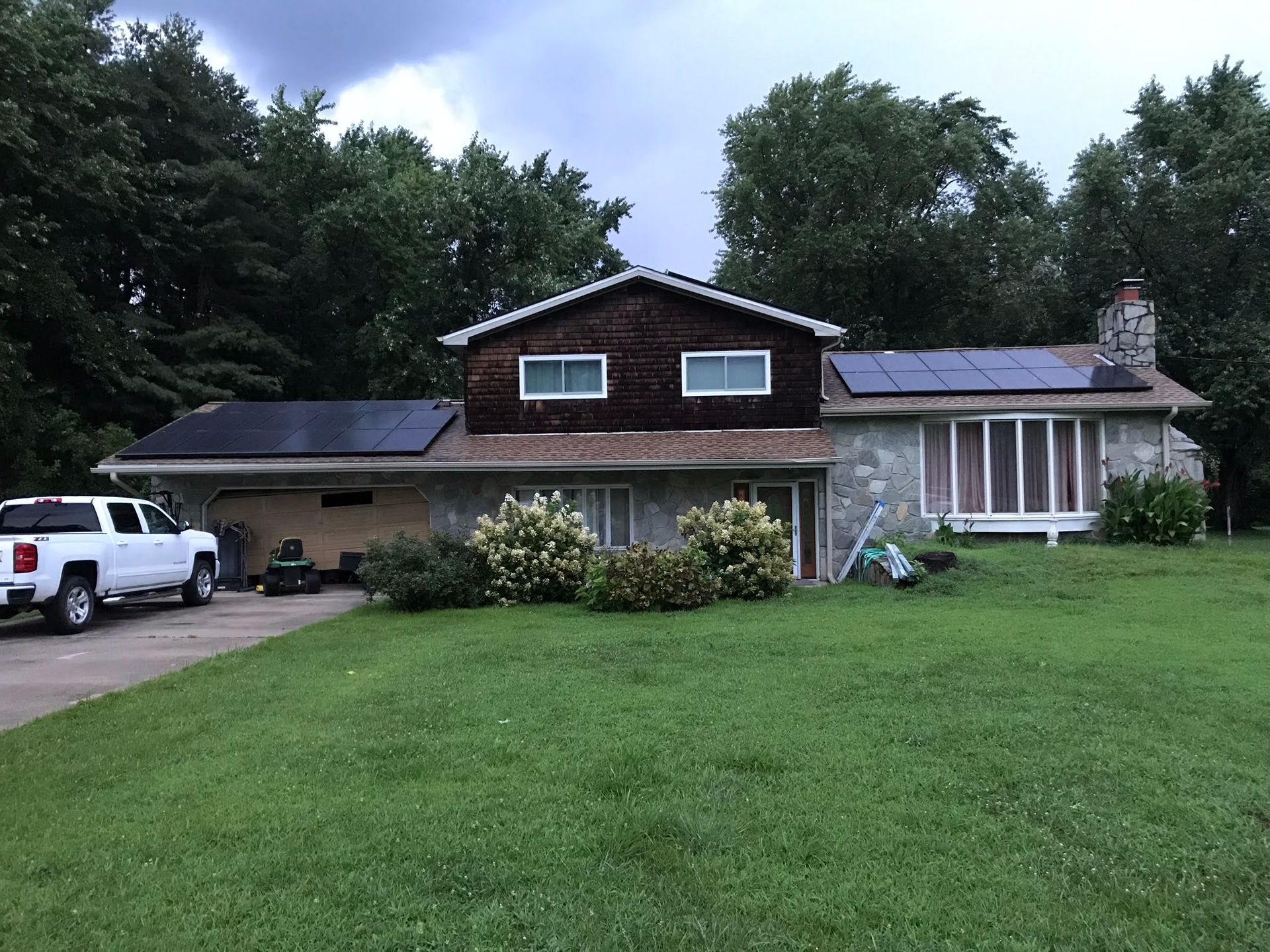 A white truck is parked in front of a house with solar panels on the roof.