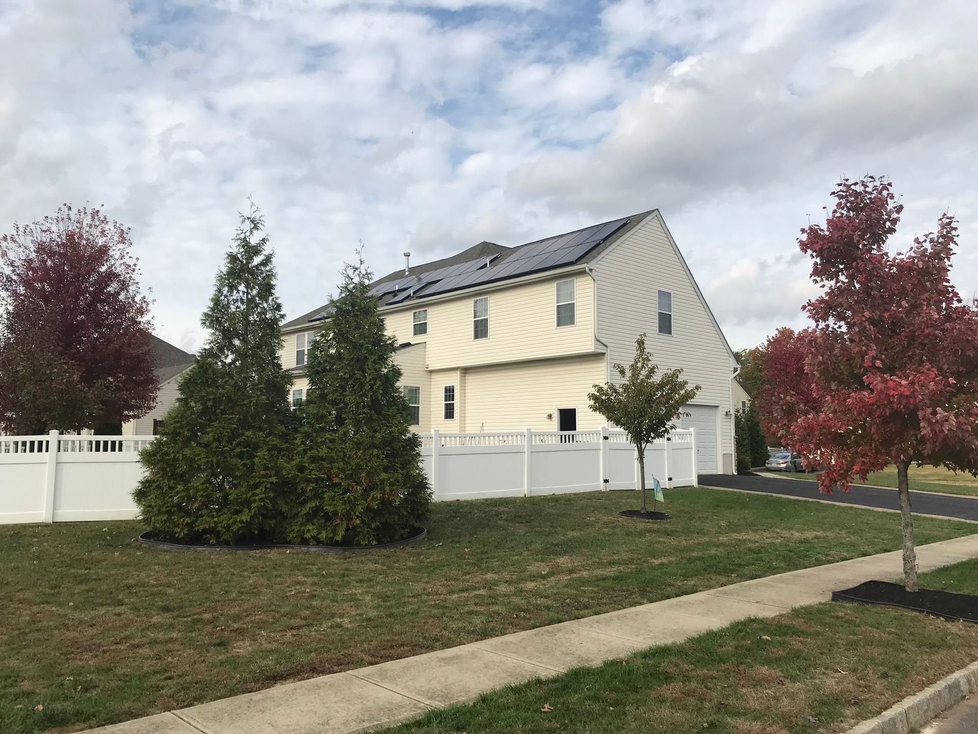 A house with a white fence and solar panels on the roof