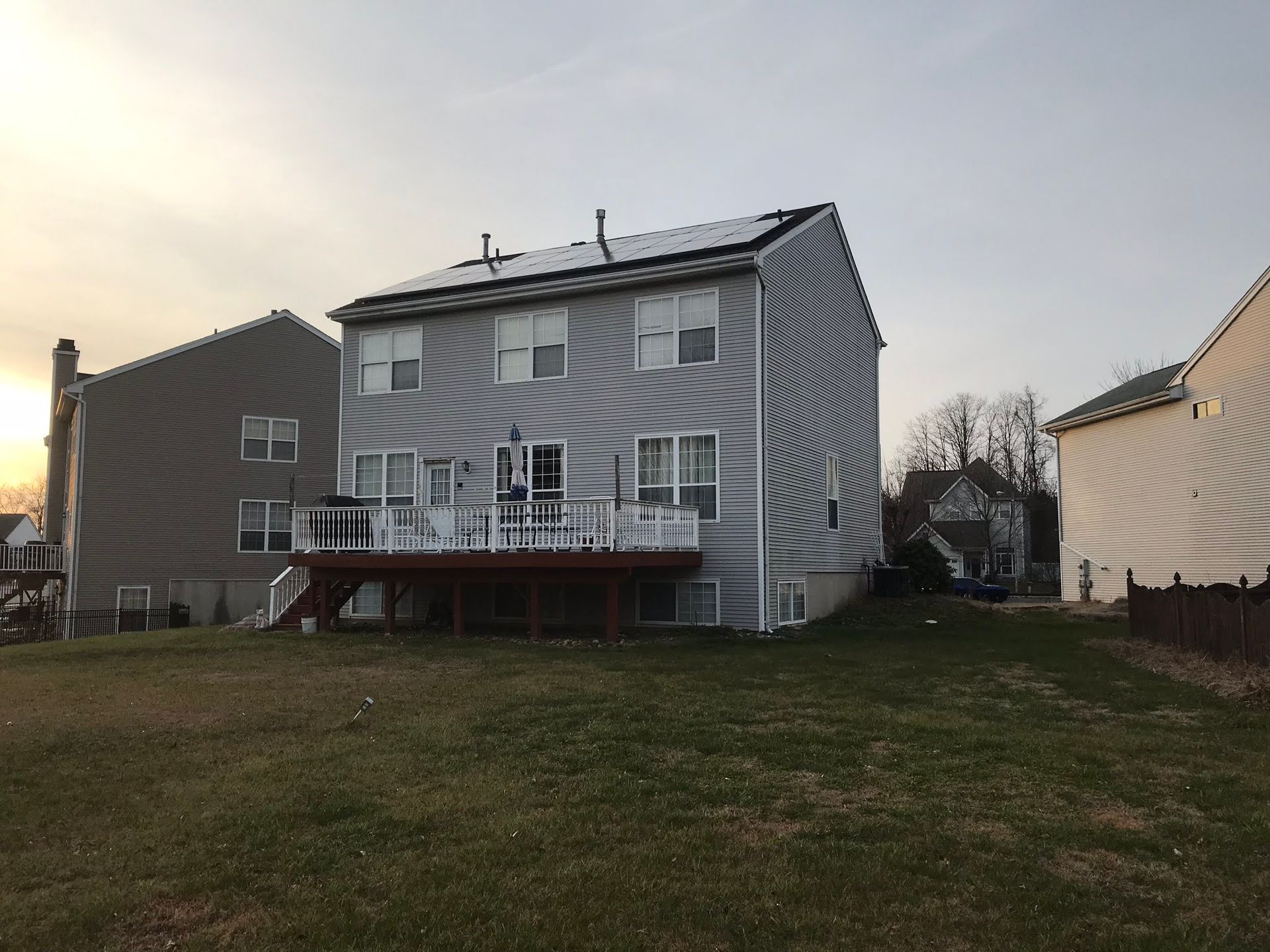 The back of a house with a deck and solar panels on the roof.