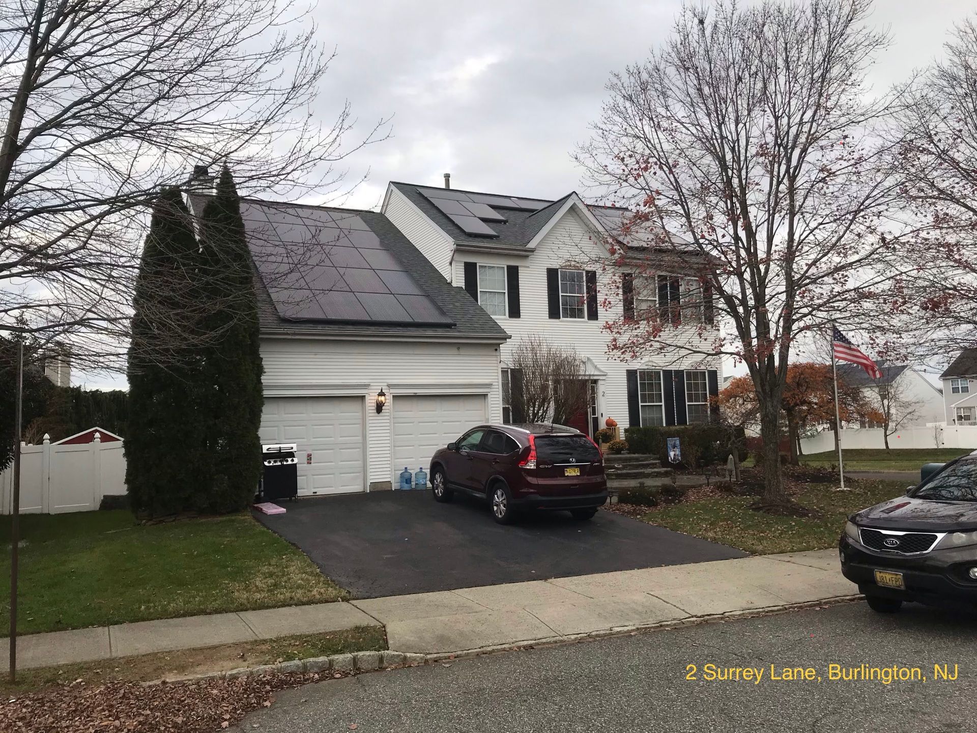A car is parked in front of a house with solar panels on the roof