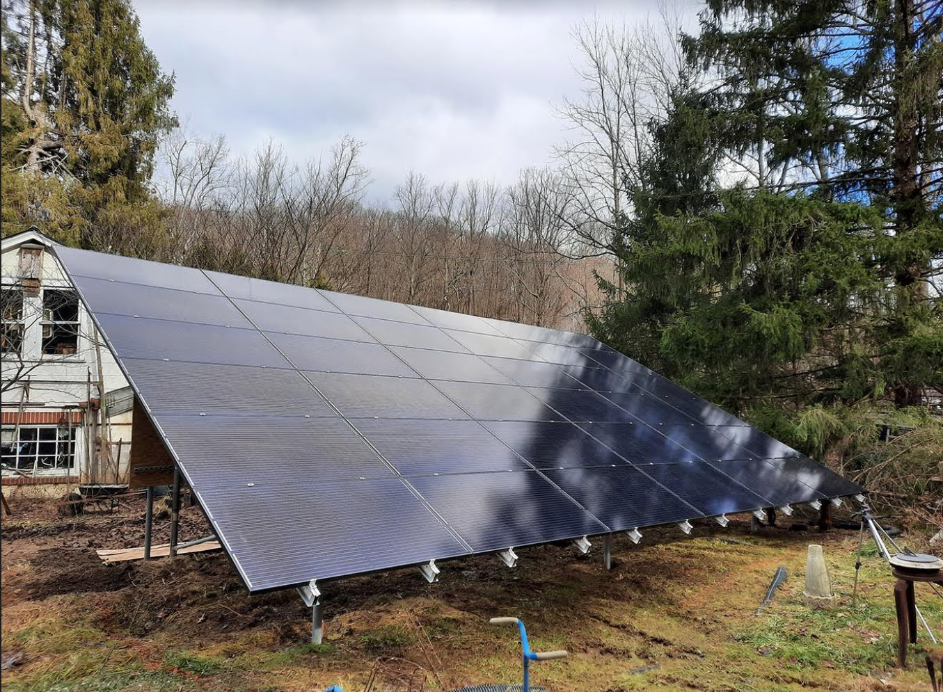 A large solar panel is sitting in the grass in front of a house.