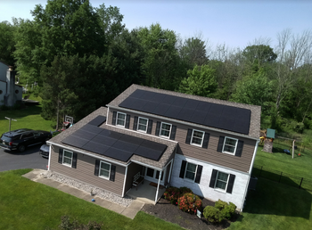 An aerial view of a house with solar panels on the roof.