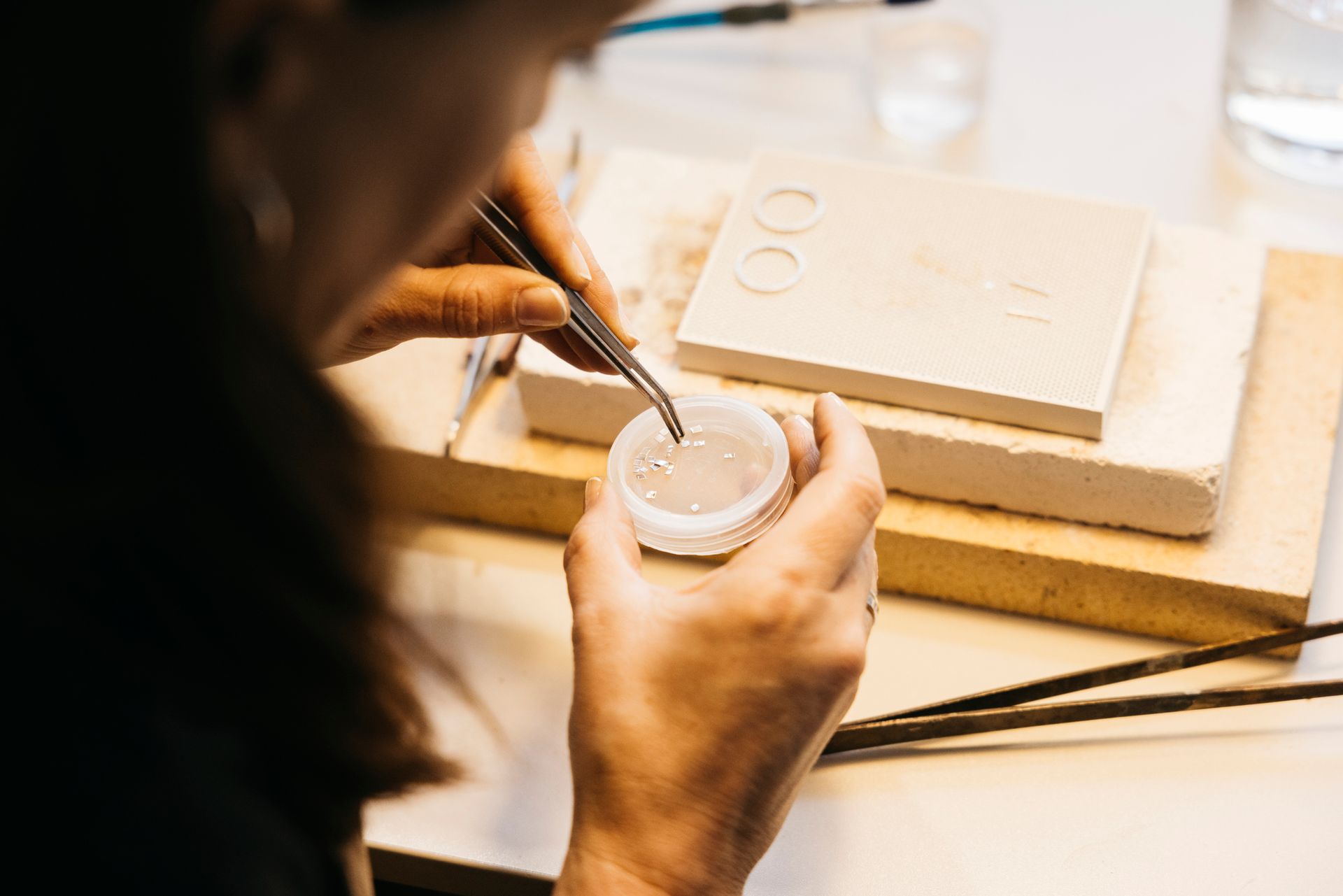 Una persona usa delle pinzette per posizionare piccoli oggetti su uno stampo.