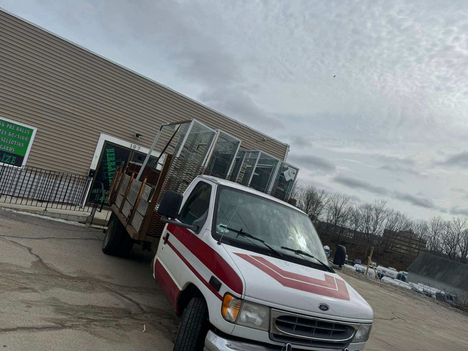 A white and red truck is parked in front of a building.