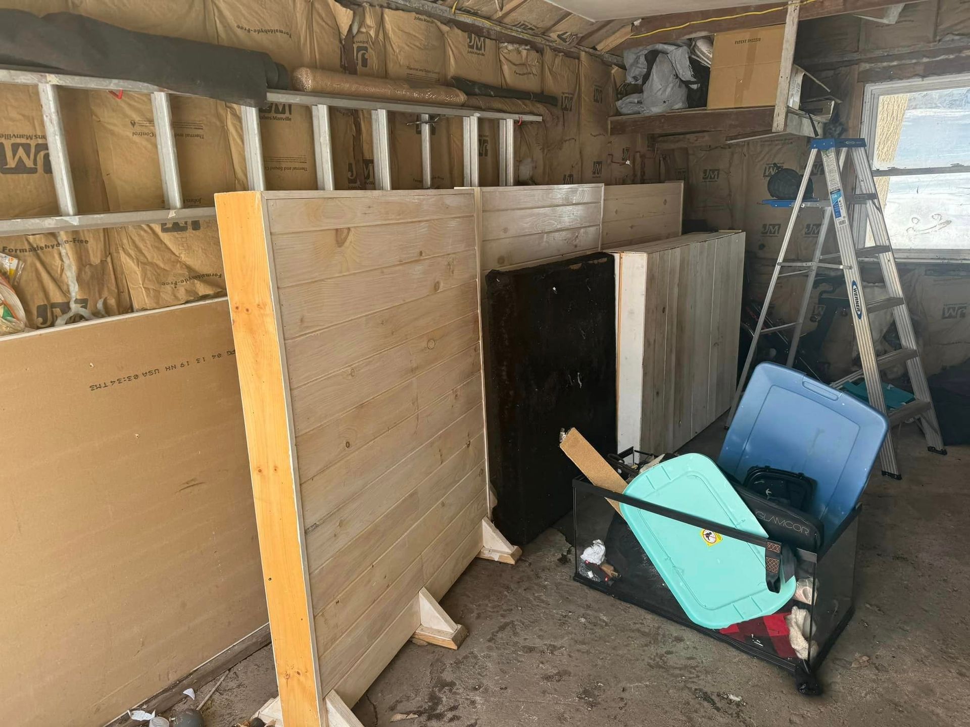 A garage filled with lots of wooden boards and a ladder.