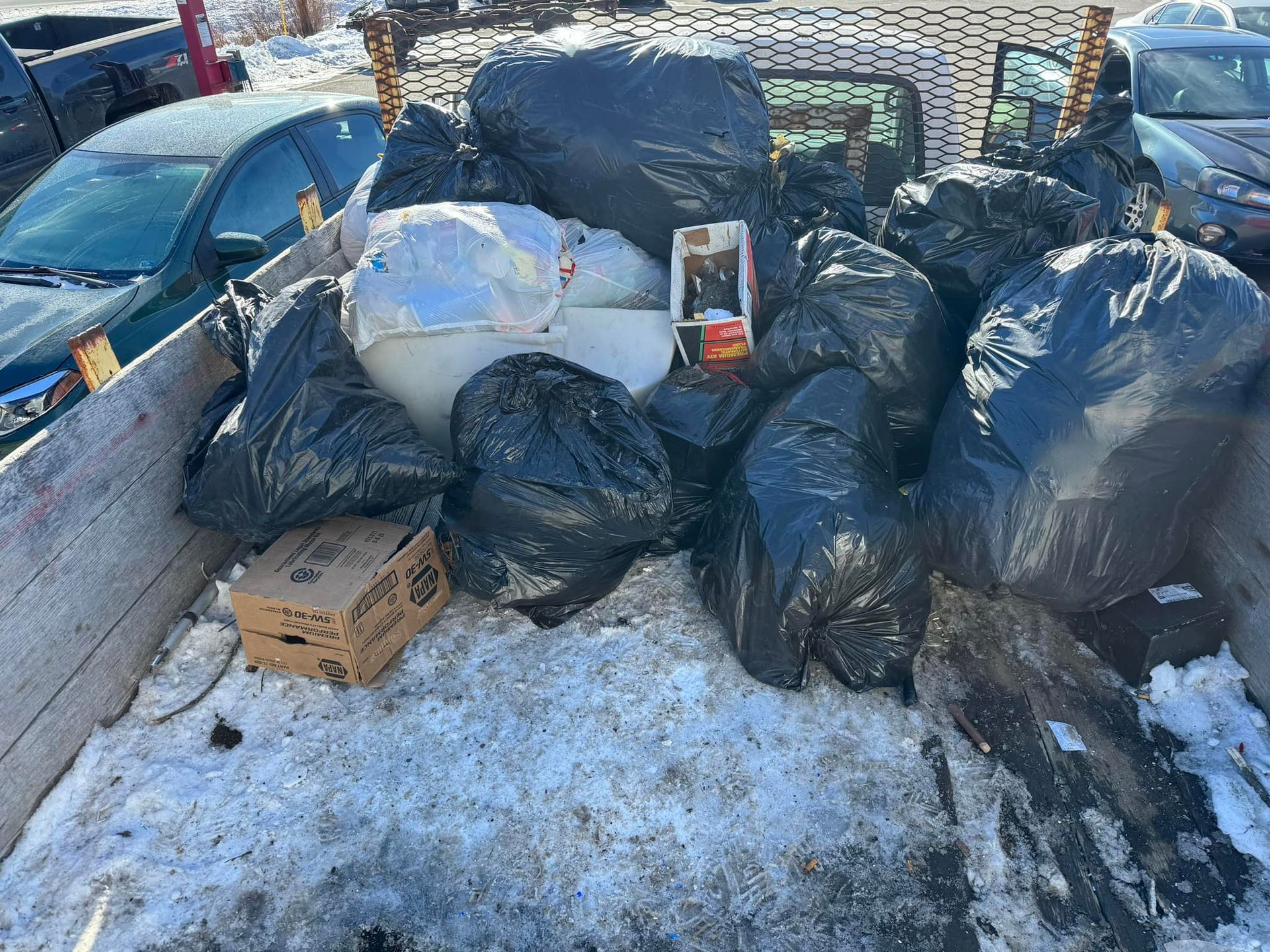 A truck full of garbage bags and boxes in the snow.