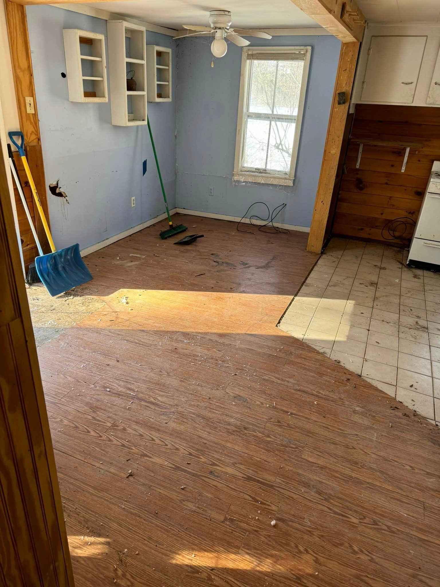 An empty room with a shovel and a broom in it.