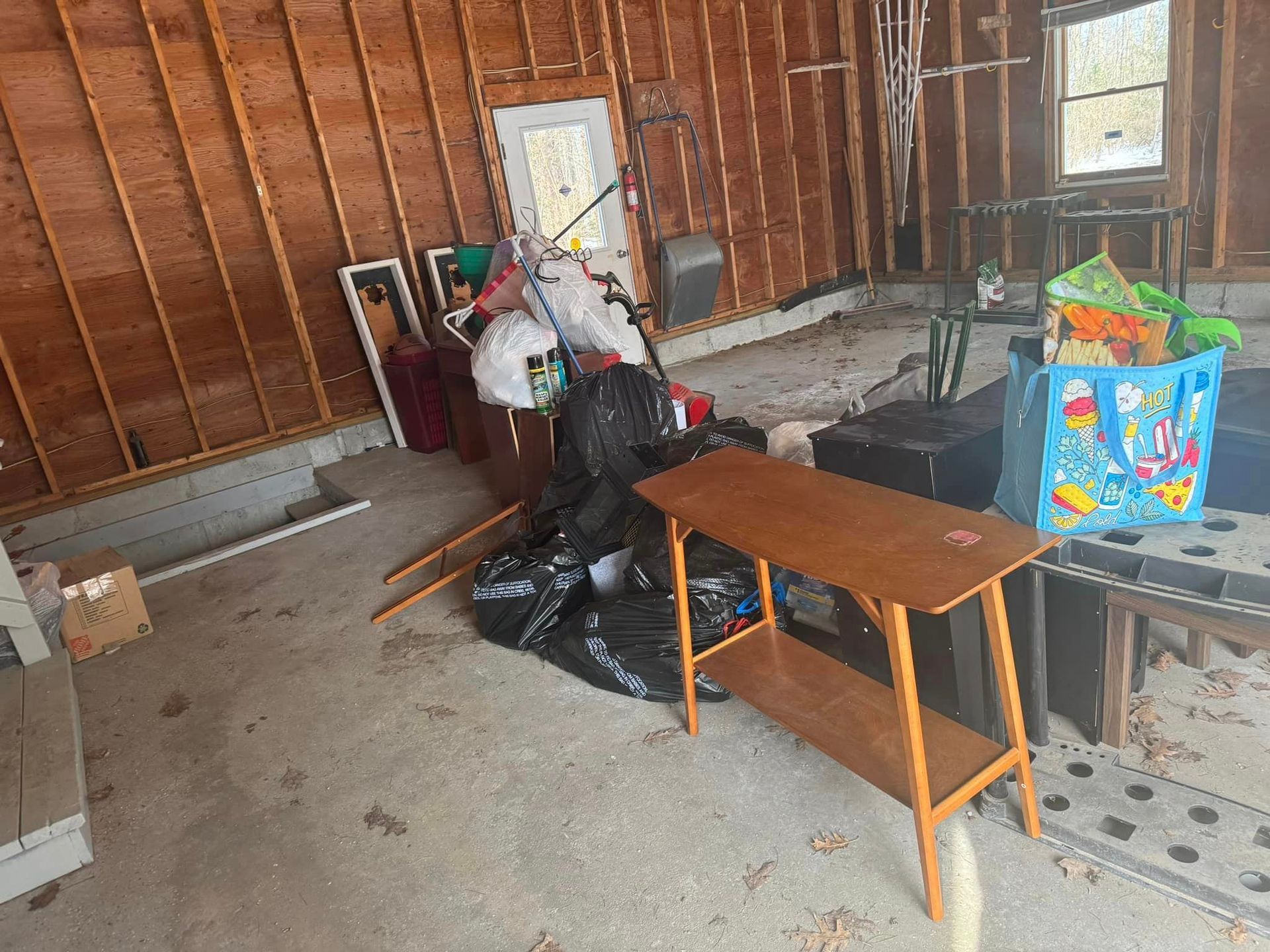 A garage filled with lots of furniture and trash bags.