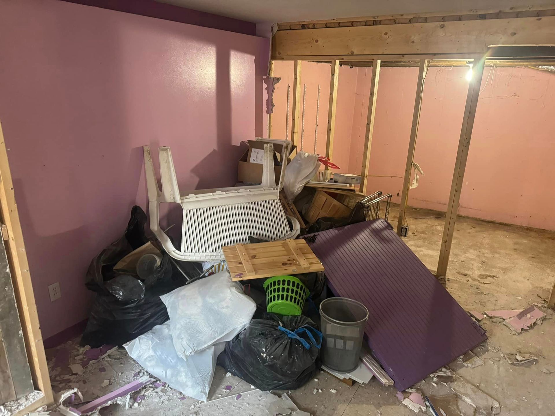 A room with pink walls and a pile of trash on the floor.