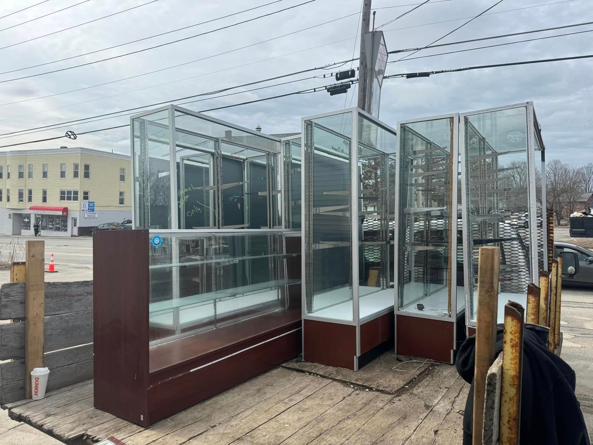 A bunch of glass display cases are sitting on the ground in a parking lot.