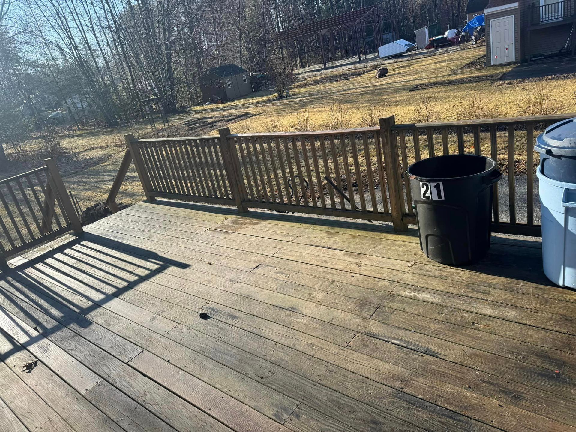 A wooden deck with a fence and a trash can on it.