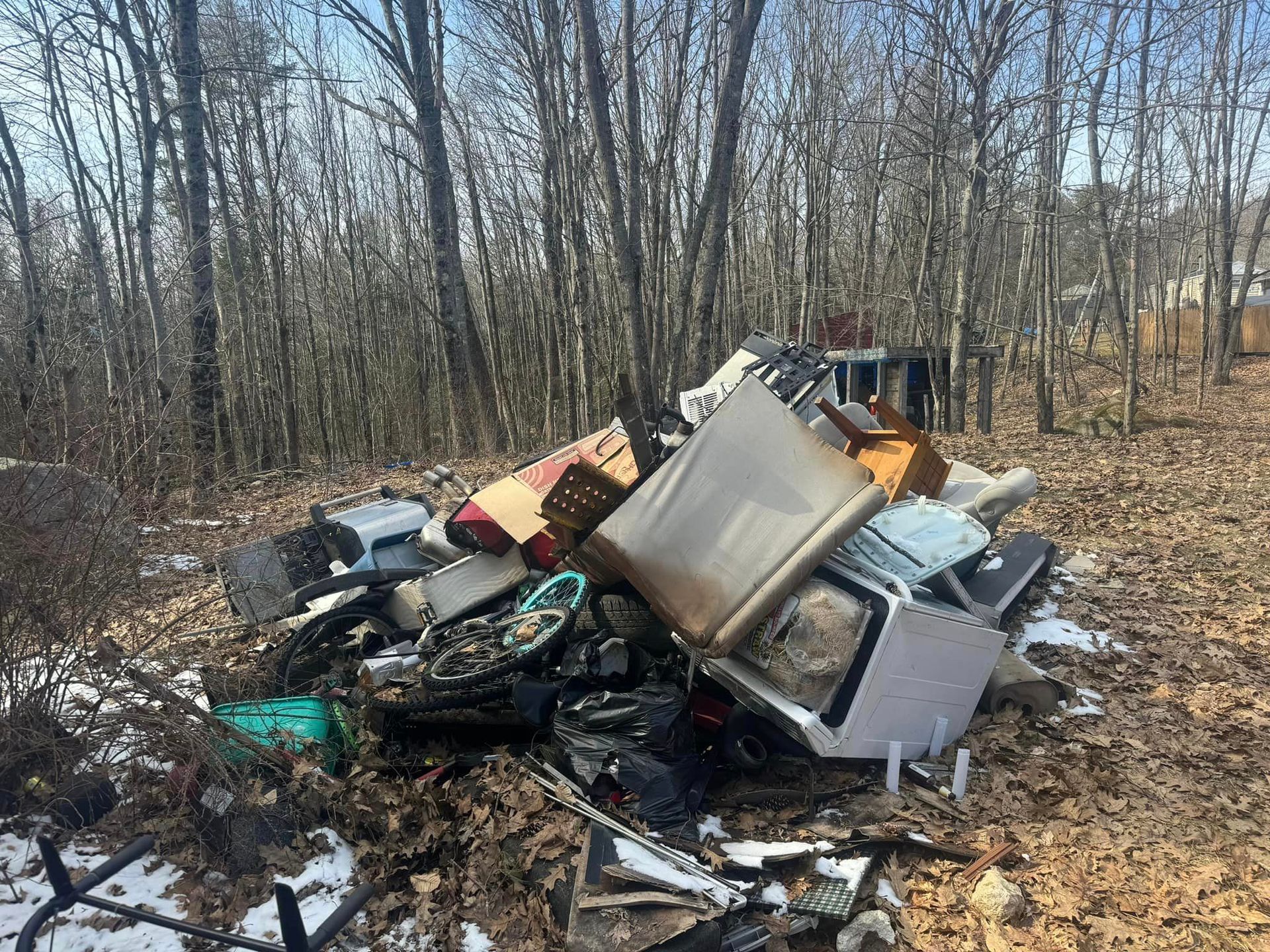 A pile of trash is sitting in the middle of a forest.