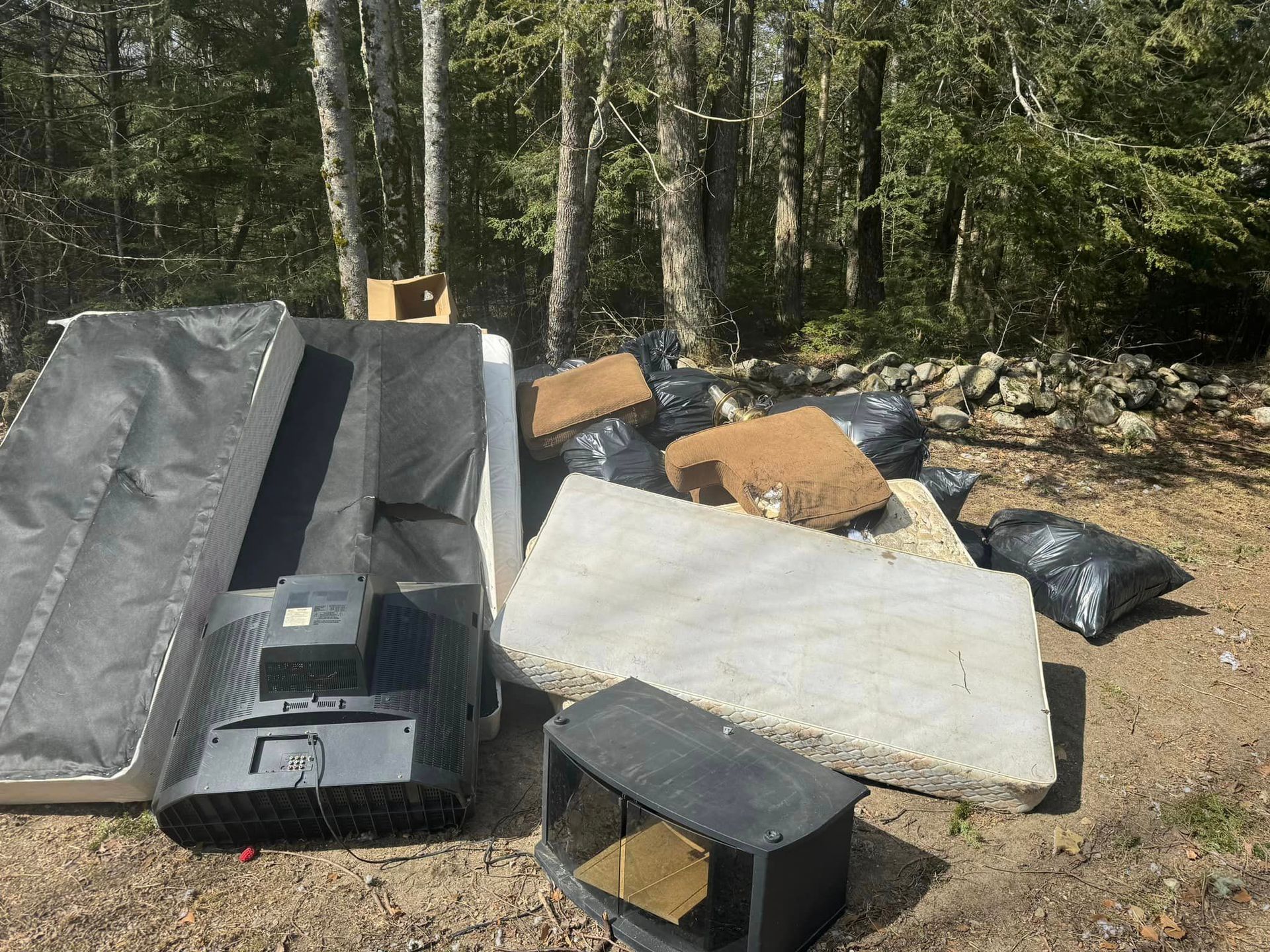 A pile of junk is sitting on the ground in the woods.