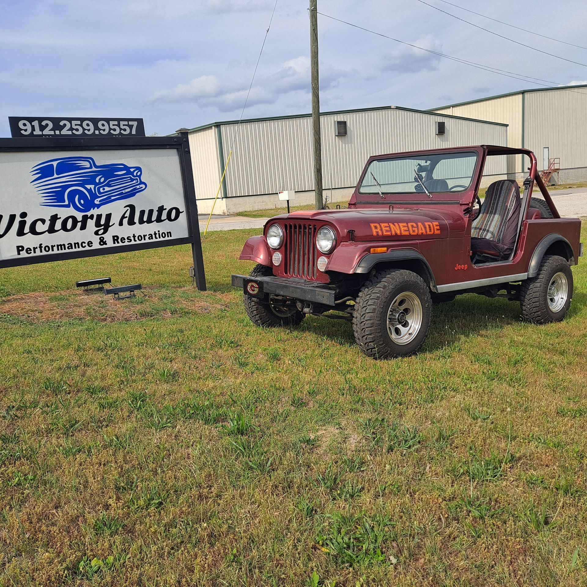 Red convertible sports car parked on grass in front of a building.