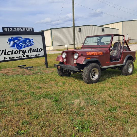 Red convertible sports car parked on grass in front of a building.