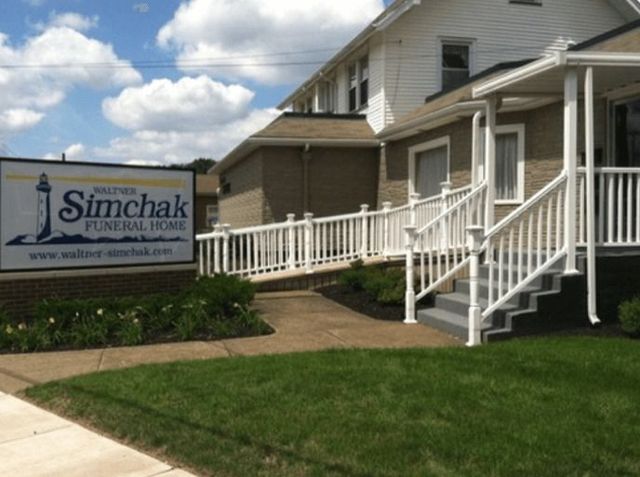 The front door of a house with a porch and plants in front of it.