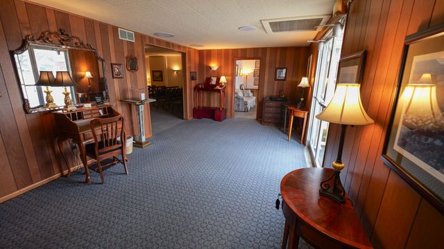 The front door of a house with a porch and plants in front of it.
