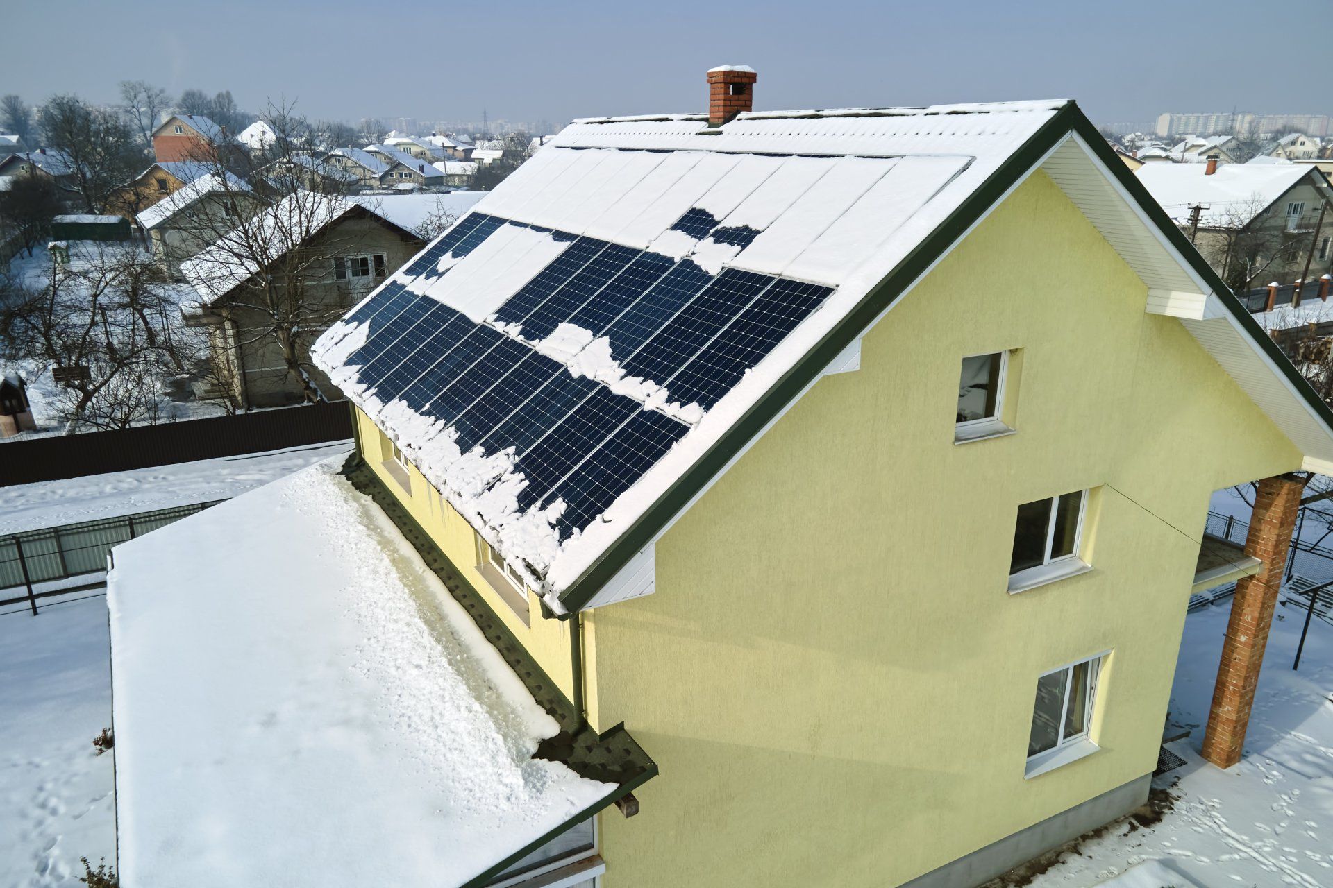a house with solar panels on the roof is covered in snow .