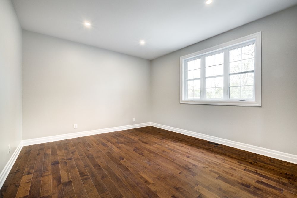 An empty room with hardwood floors and a coffered ceiling.