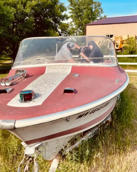 A red and white boat is parked in a grassy field