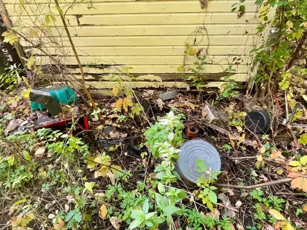 a pile of trash is sitting in front of a yellow building .