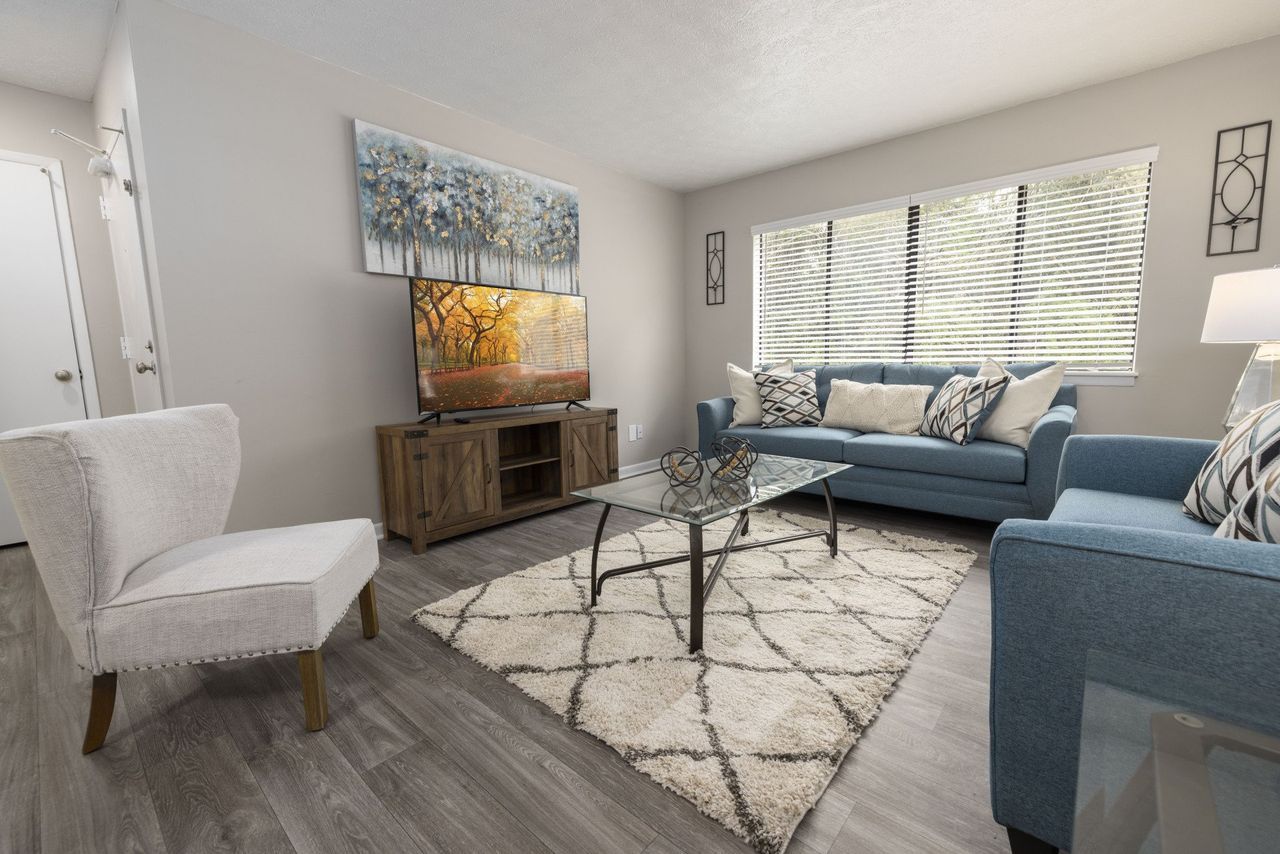 A living room with a couch , chair , coffee table and television at Cross Creek.