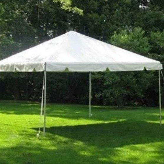 A white tent is sitting in the middle of a lush green field.