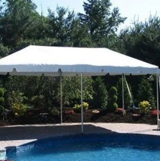 A white tent is sitting next to a swimming pool.