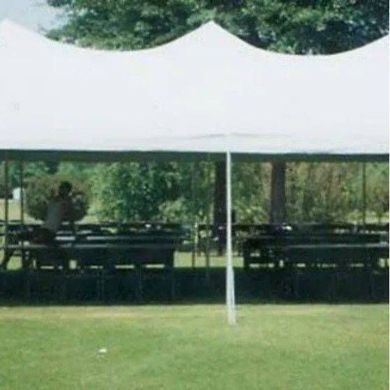 A white tent is sitting in the middle of a grassy field.