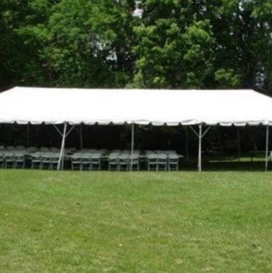 A large white tent is sitting in the middle of a grassy field.