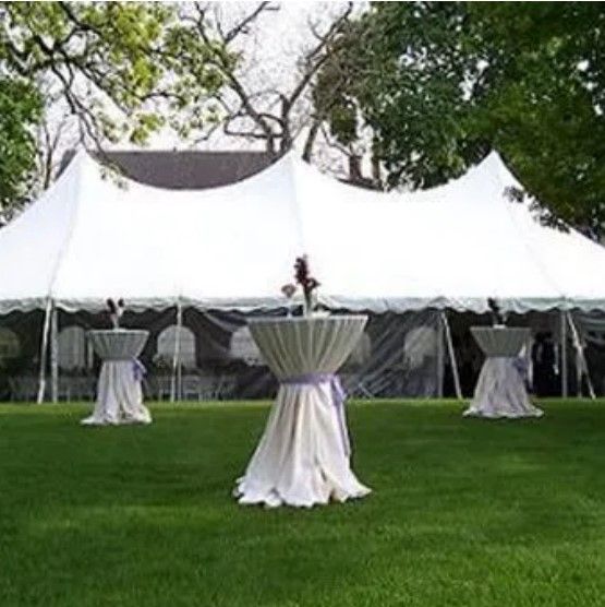 A white tent with tables underneath it in a grassy field.