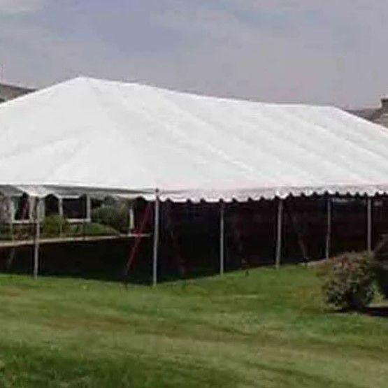 A large white tent is sitting in the middle of a lush green field.