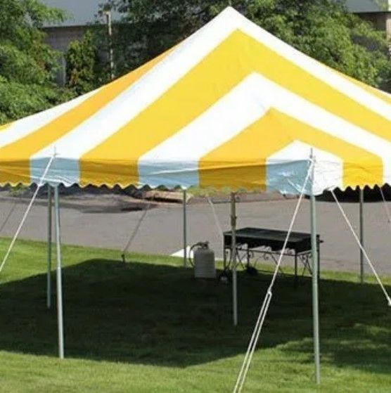 A yellow and white striped tent is sitting in the grass