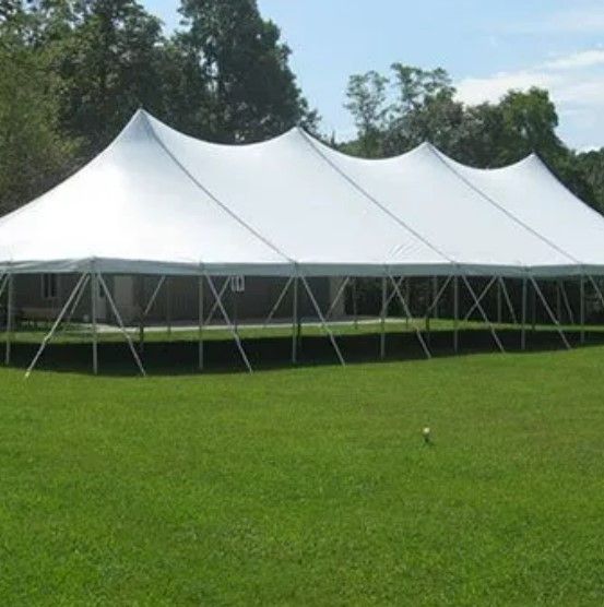 A large white tent is sitting in the middle of a grassy field.