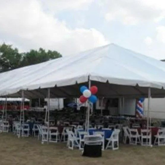 A large white tent with tables and chairs underneath it