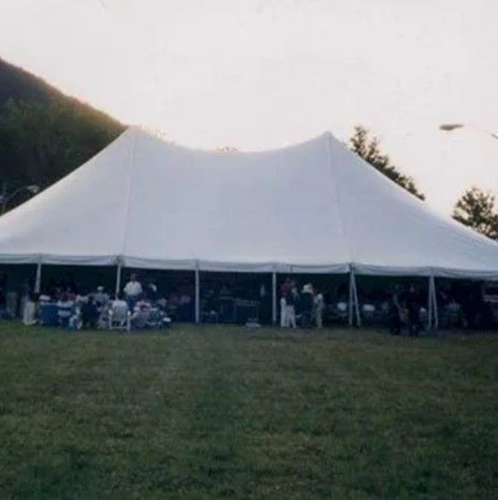 A large white tent is sitting in the middle of a grassy field.