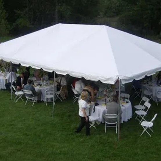 A large white tent is sitting on top of a lush green field.