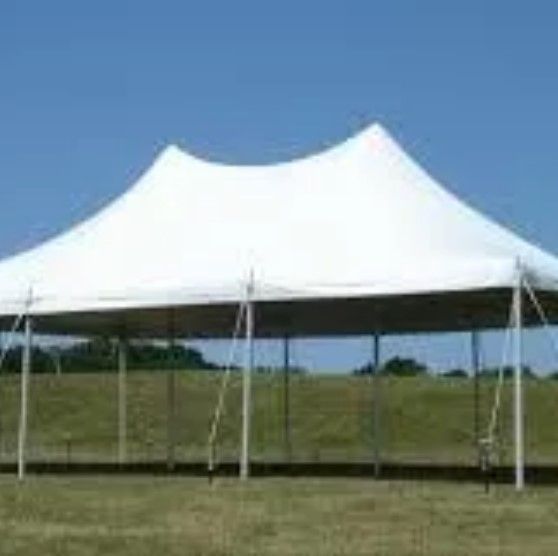 A large white tent is sitting in the middle of a grassy field.