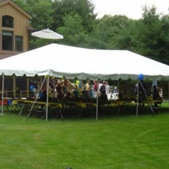 A large white tent with tables and chairs underneath it