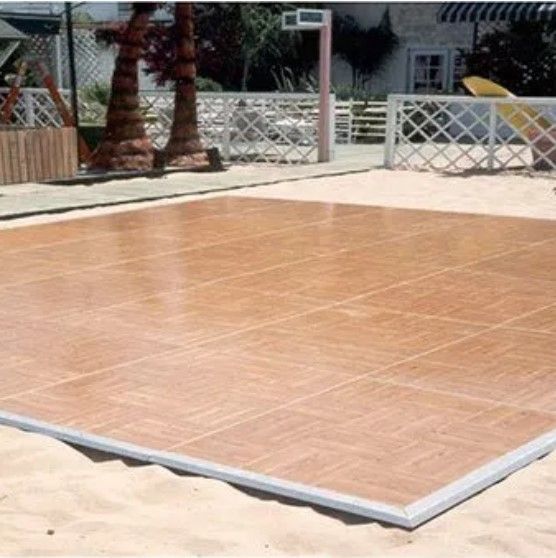 A large wooden dance floor is sitting on a sandy beach